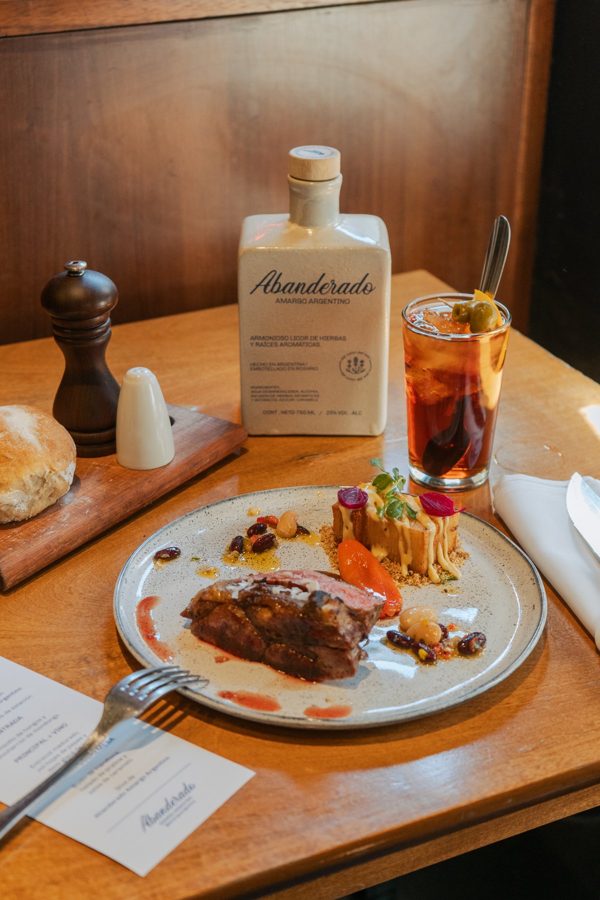 La botella de Abanderado sobre la mesa, con un trago servido y el pan de la casa