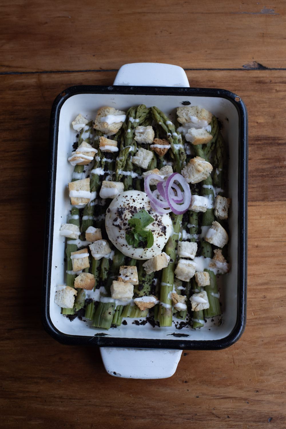 Fuente de vegetales asados con huevo poché servida en la mesa