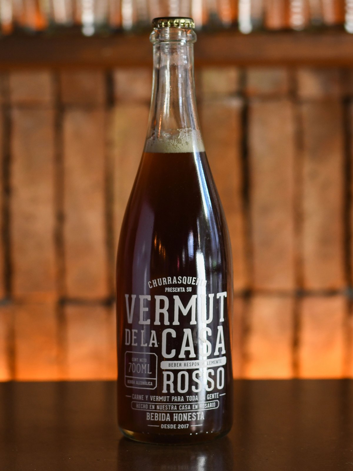 La botella del vermut Rosso de la casa sobre la barra, con el horno encendido detrás